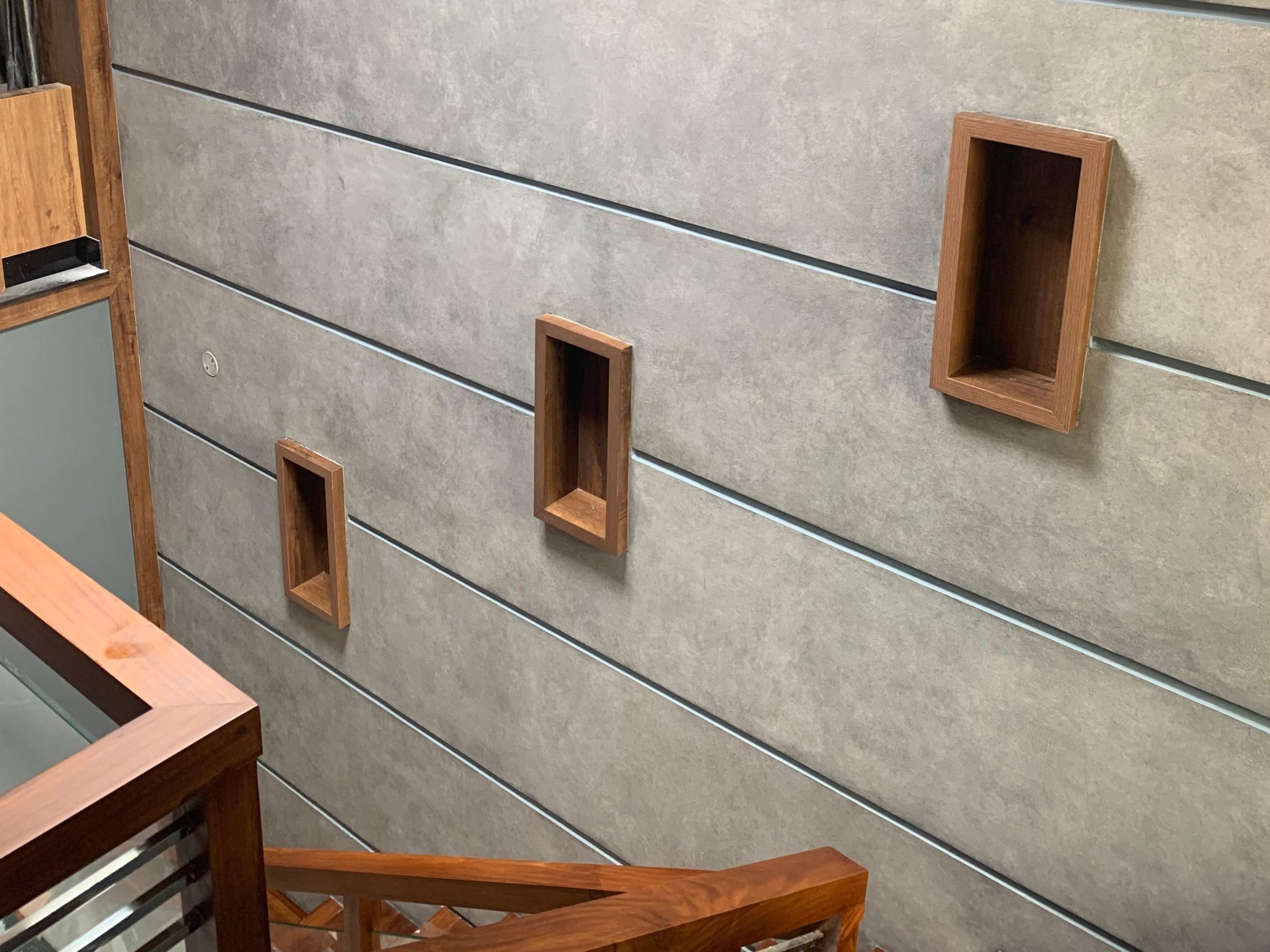 Modern staircase wall with grey wallpaper and wooden decorative boxes.